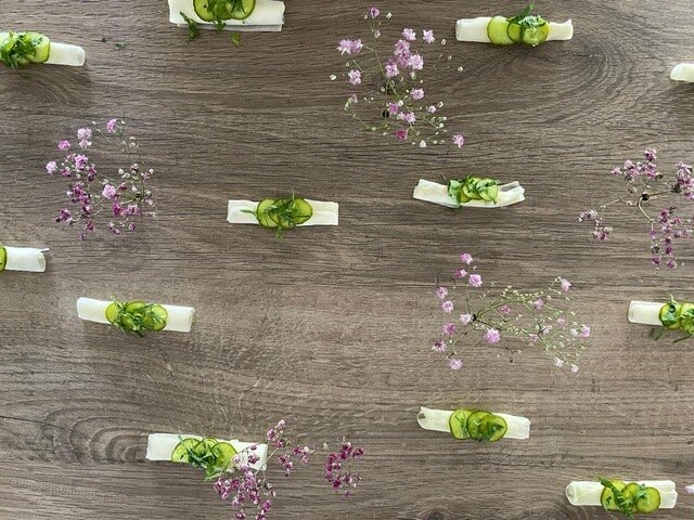 Reihen feiner Amuse-Bouches mit Kräuterblüten auf Holz angerichtet